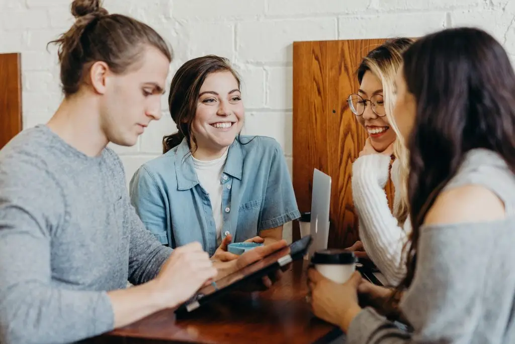 About Us - a group of people sitting around a table